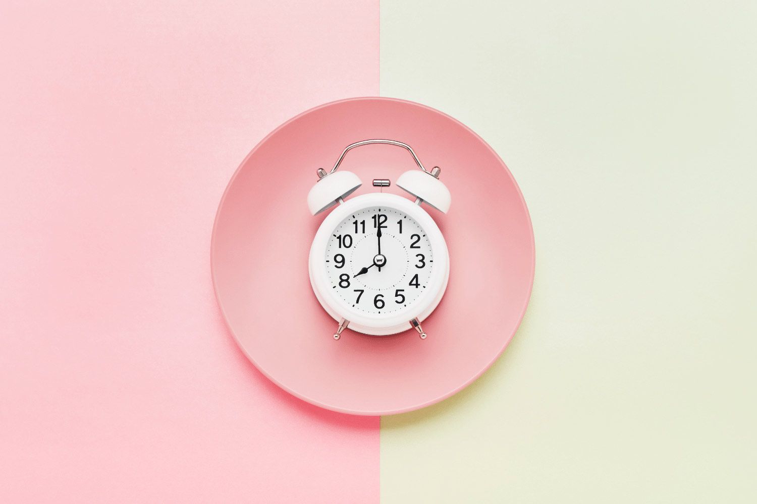 Concept art for intermittent fasting for women, a an alarm clock sits on a pink dinner plate.